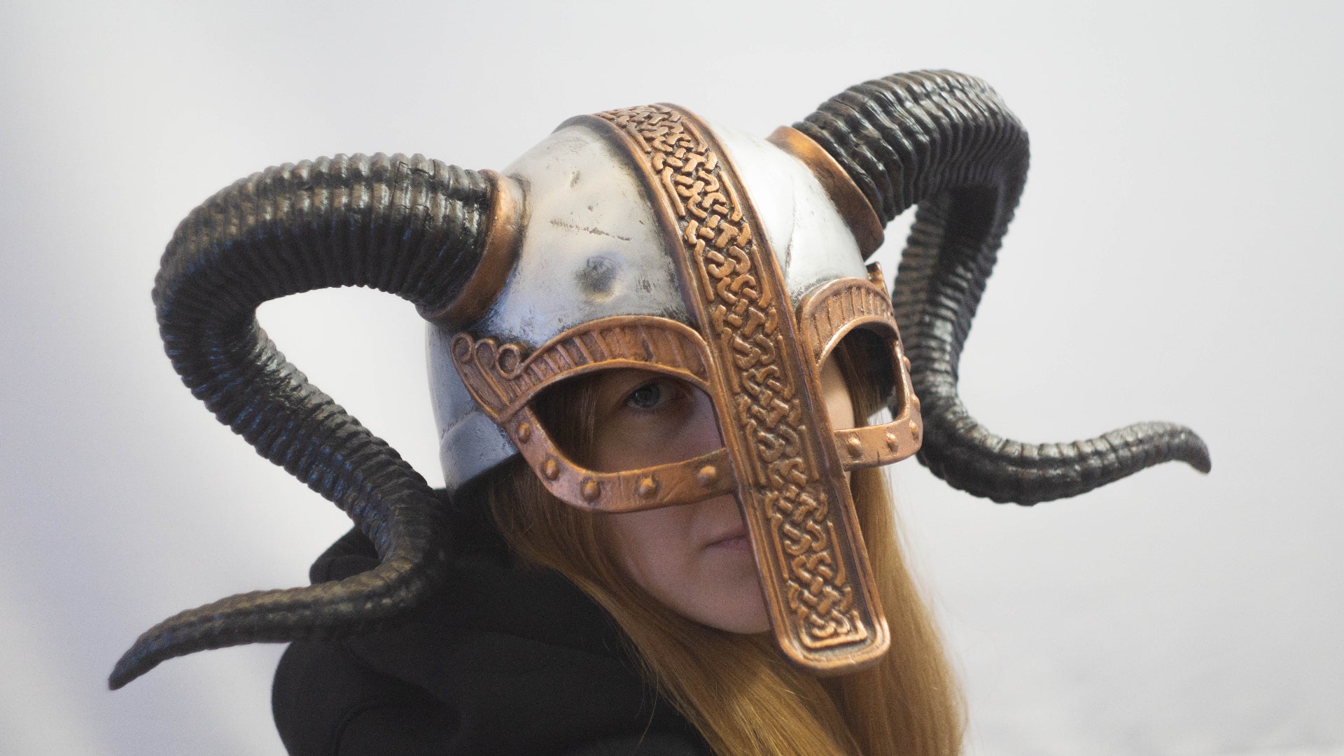 Person wearing a helmet with ram horns on a plain background