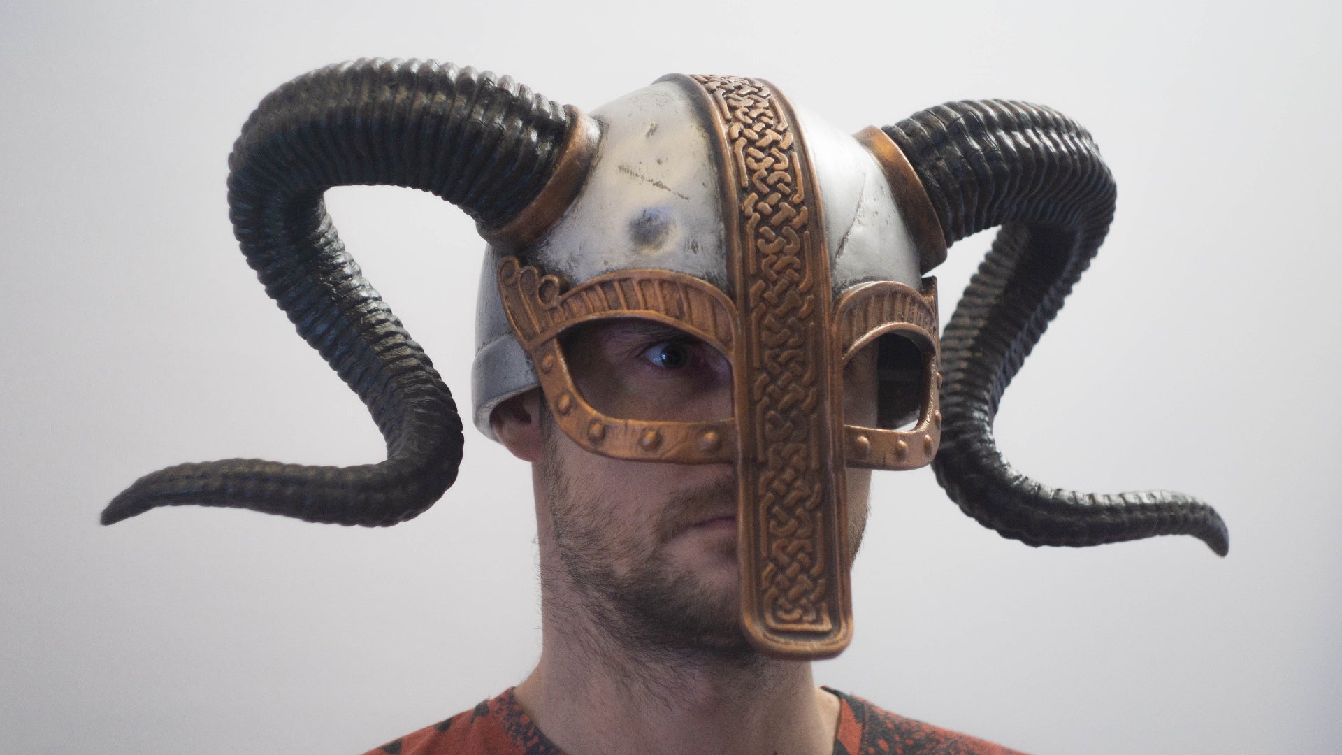 Person wearing a detailed helmet with ram horns on a plain background