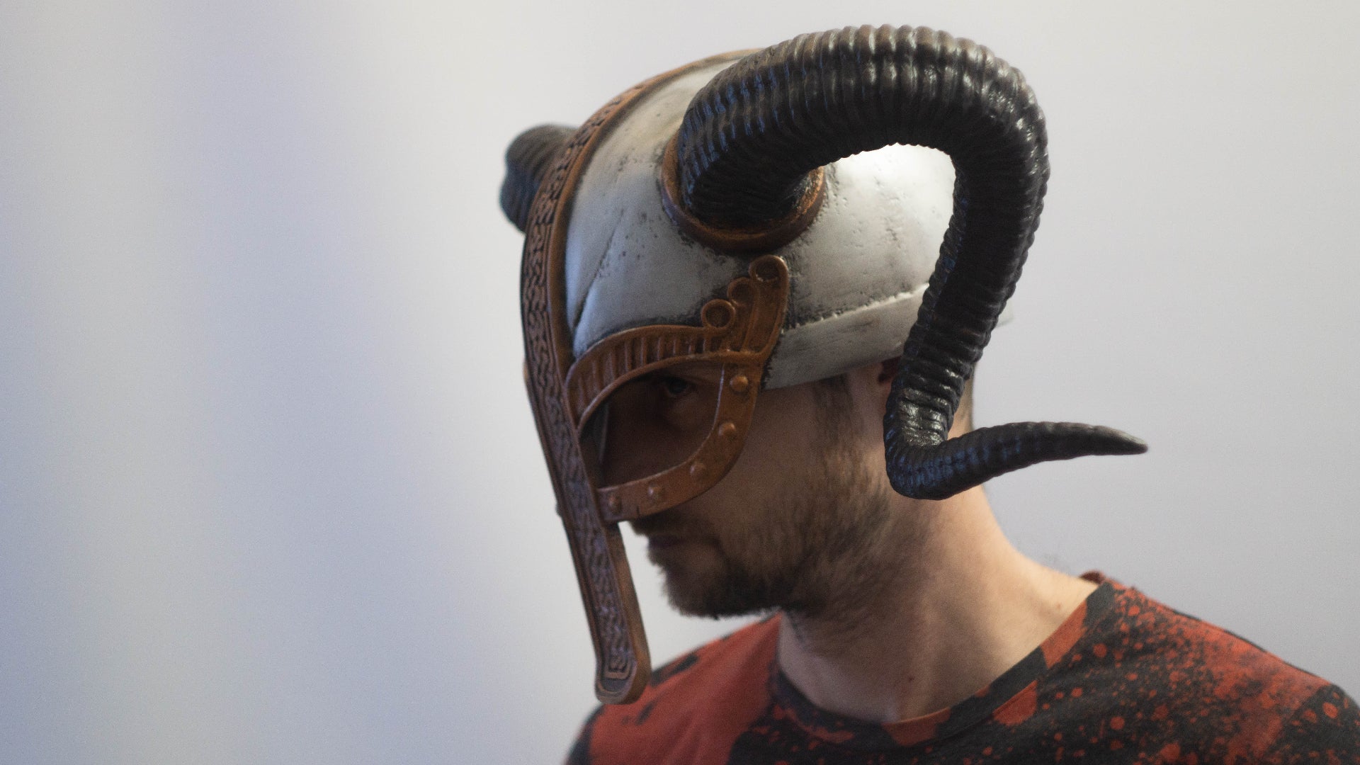 Person wearing a helmet with large horns against a plain background
