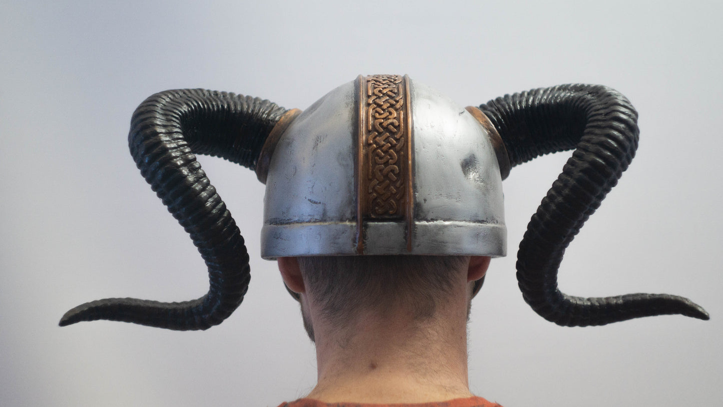 Person wearing a helmet with decorative horns on a plain background