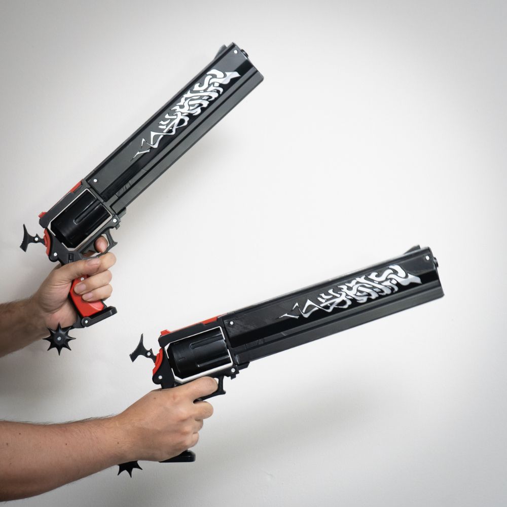 Two toy guns with decorative designs held by a person against a white background