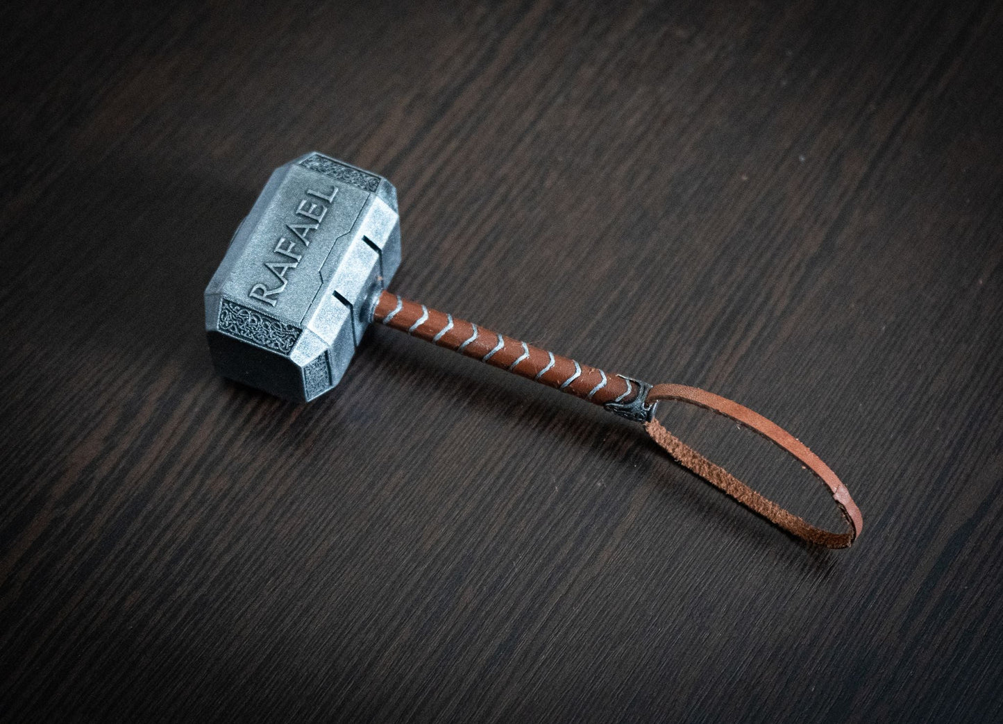 Thor Hammer Miniature 1:4 scale hand-painted Mjolnir replica with personalized engraving and leather strap on dark wood surface