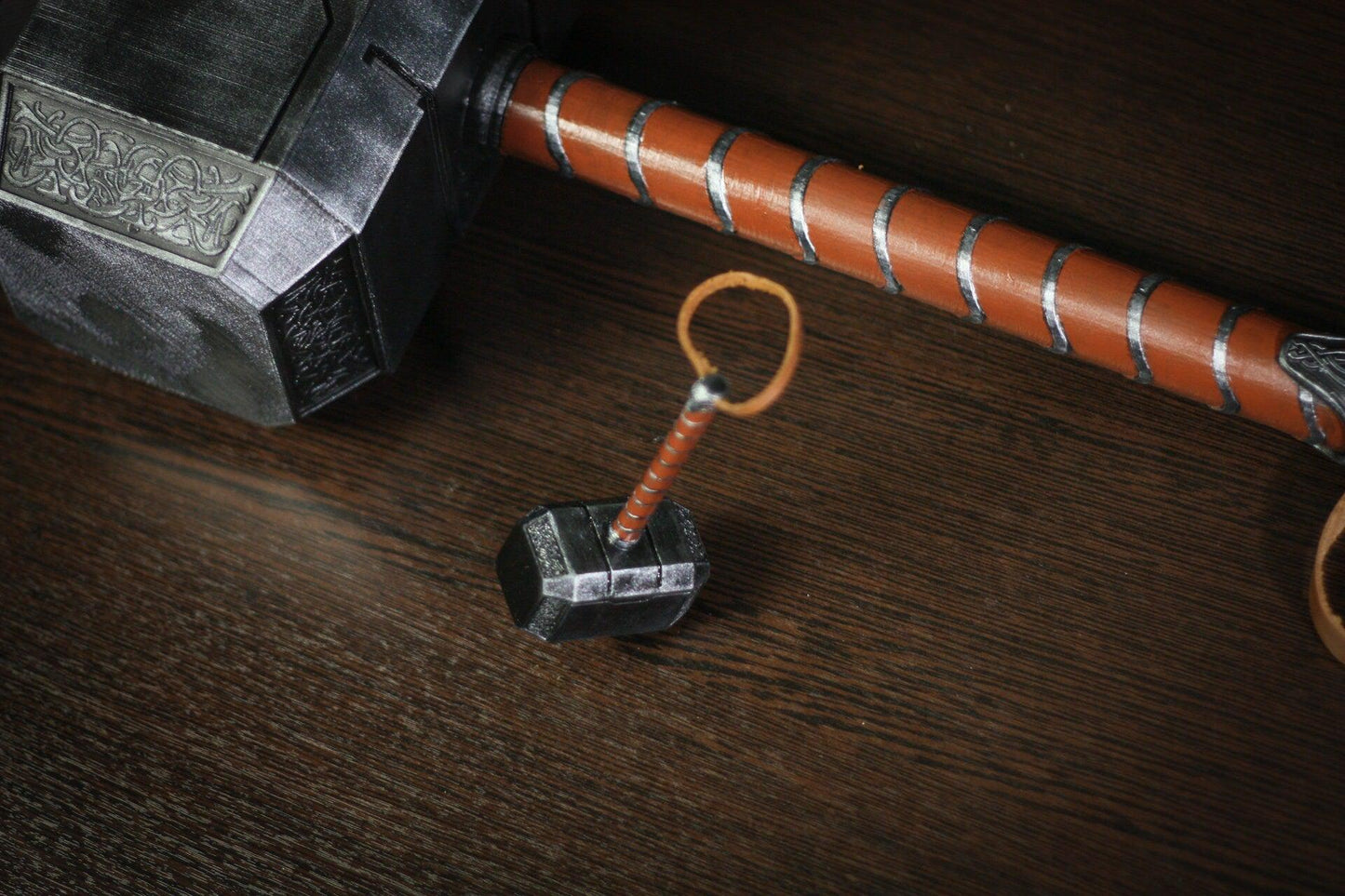 Miniature 1:4 scale Thor hammer replica with detailed silver head and brown handle on wooden surface